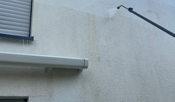 Reinigung einer schmutzigen Fassade mit Moosbefall